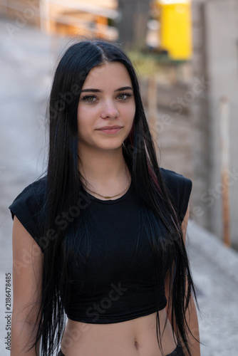 Young woman with long black hair posing outdoors in soft light
