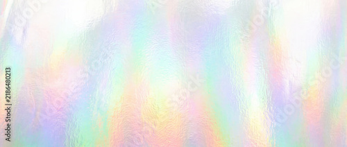 Holographic film rainbow surface texture. Pastel colored iridescent foil backdrop. Abstract glowing metallic gradient background