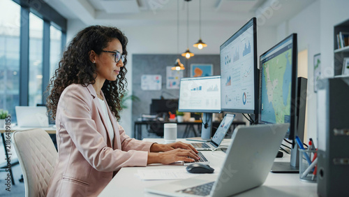 Professional woman with curly hair working on a computer in a modern office space