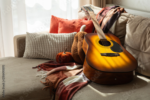 Cuadro en lienzo Acoustic guitar resting on a sofa with decorative pumpkins and a warm blanket du