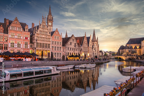 Golden evening light gilds Ghent's iconic Graslei skyline reflected in the Leie river