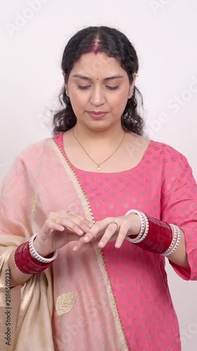 Vertical Shot of Married Indian Woman Adjusting Gold Rings and Traditional Bridal Chuda Bangles