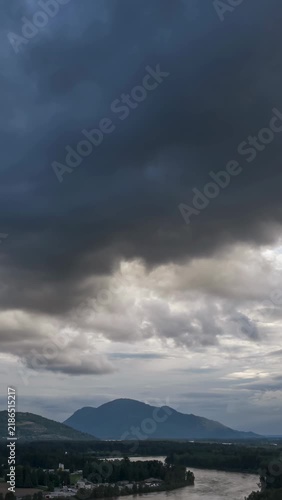 Dramatic Clouds Sweep Across Chilliwack's Fraser Valley with Mountains and River Below in British Columbia