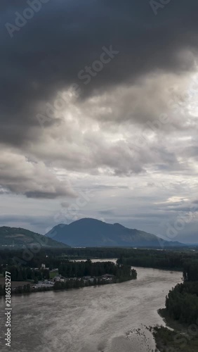 Aerial View of Fraser River Winding Through Chilliwack, British Columbia with Majestic Mountains and Dramatic Clouds