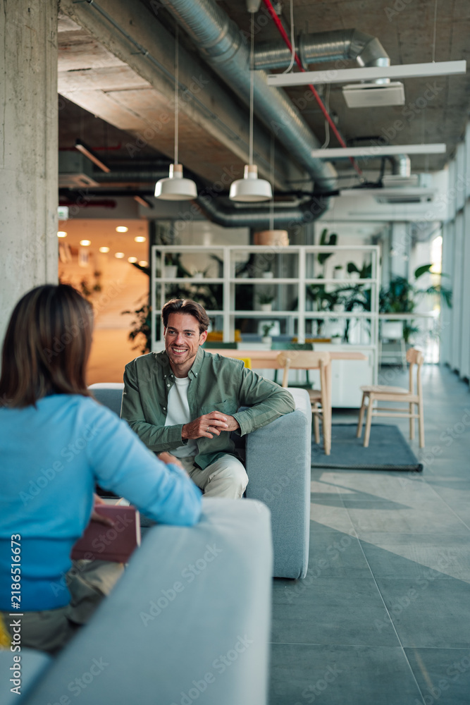 Fototapeta premium Coworkers meeting in a modern office space, man listening and smiling during a professional business discussion