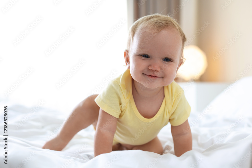 Fototapeta premium Cute little baby in onesie on bed at home