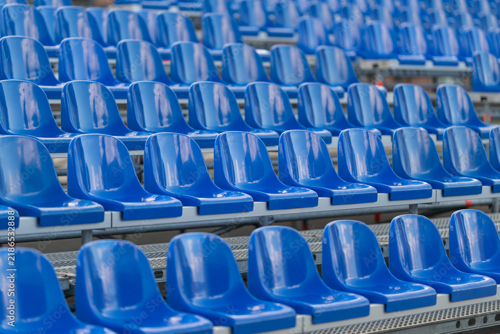Fototapeta premium Rows of vibrant blue seats await eager spectators at a lively sports stadium on a bright sunny day