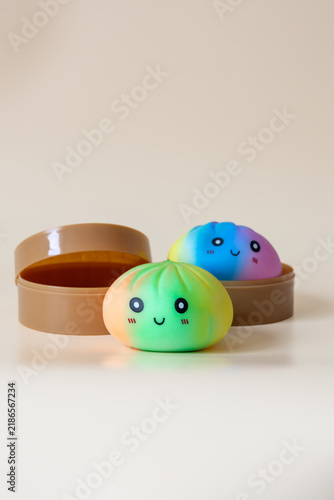 Two colorful dumpling shaped squishy toys with smiling faces in plastic steamer baskets