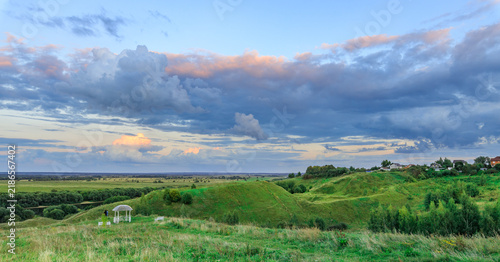 Vast meadow under colorful evening sky with grazing sheep
