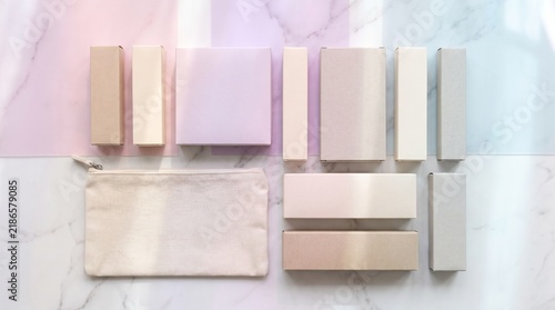 Flat lay of cosmetic packaging and makeup bag on a marble background with pastel color accents