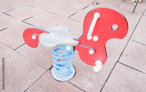 Cuadro en lienzo A red animal-shaped spring rider toy with a blue spring on a rubber-tiled playground surface