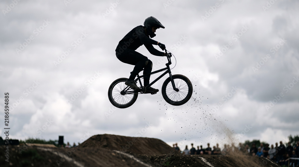 Fototapeta premium BMX rider performs a jump against a cloudy sky