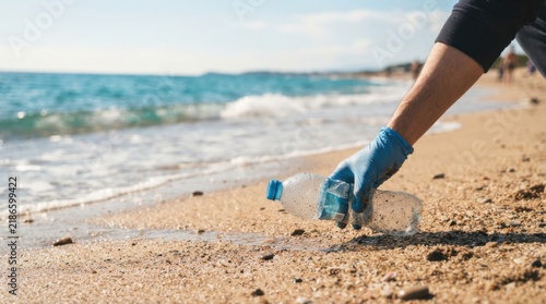 Person Picking Up Plastic Water Bottle from Sandy Beach