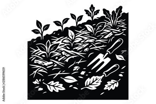 Small garden hand fork lying on mulched soil with growing vegetable seedlings