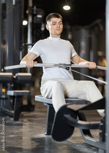 Fotografía In gym, guy uses cable row machine to strengthen arm muscles