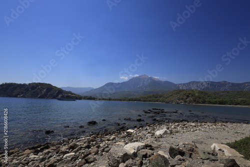 Tranquil coastal landscape of Phaselis cove surrounded by pine trees, blue Mediterranean sea, and mountain range in Antalya
