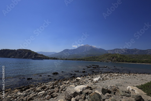 Tranquil coastal landscape of Phaselis cove surrounded by pine trees, blue Mediterranean sea, and mountain range in Antalya