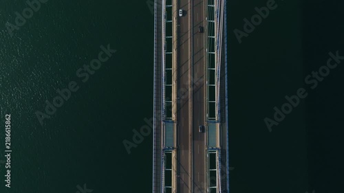 Perfectly symmetrical top-down aerial view of the Rande Bridge near Vigo, Spain, capturing the rhythmic flow of traffic against the deep, dark expanse of the estuary below