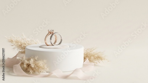 Diamond engagement ring and wedding band on white podium with pampas grass and ribbon, elegant bridal jewelry display for marriage proposal.