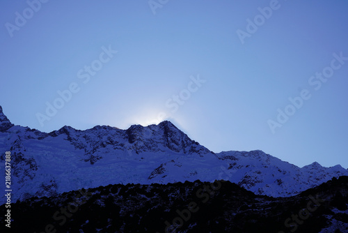 Foto Sunrise over snowbound mountain ridge beneath clear blue sky illuminating rugged