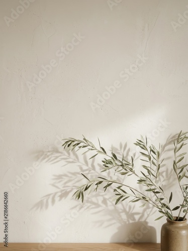 Soft natural light illuminates delicate olive branches in a simple ceramic vase, casting long, elegant shadows against a textured neutral