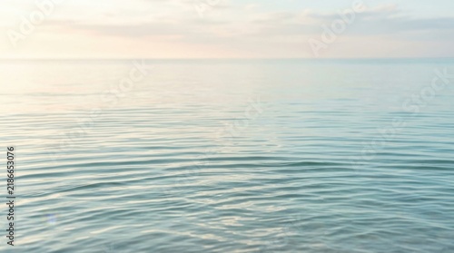 Calm rippling water surface at sunset with soft pastel light reflecting on gentle waves for peaceful and serene natural background imagery