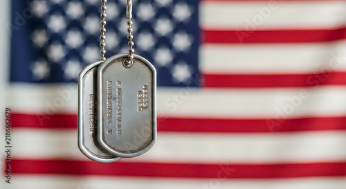 Military dog tags hanging in front of the american flag for veterans day
