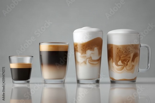 Four layered coffee drinks in clear glasses with milk foam on a reflective gray surface