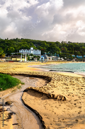 Fototapeta kuchenna View across the sandy La Toc Beach towards a tropical resort surrounded by lush green hills in Saint Lucia.