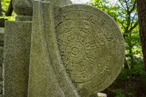 Obraz na plátně A Buddhist wheel of dharma is delicately carved into a mossy stone bridge balustrade at a traditional Korean temple entrance