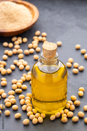 Soybean oil bottle surrounded by soybeans on a dark background, healthy eating concept and natural vegetable oil.