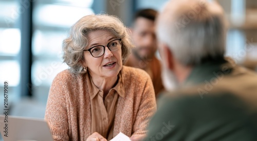 Senior woman with glasses consulting with clients in a modern office space