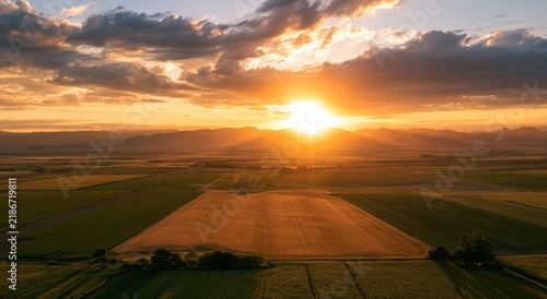 Golden sunset over expansive agricultural farmland with rolling hills