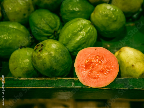 Obraz na płótnie Fresh green guavas with a cut pink half in a wooden box