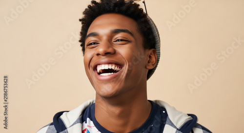 Young Black man laughing with genuine expression against a neutral background