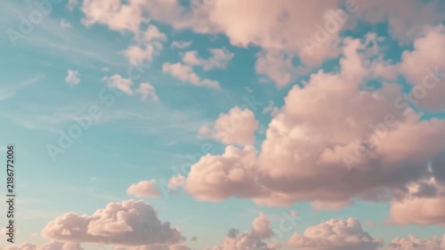 Fluffy pink clouds drift across a bright teal sky