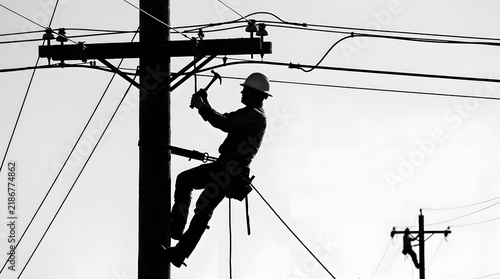 Lineman wearing a hard hat repairing power lines on a utility pole silhouette