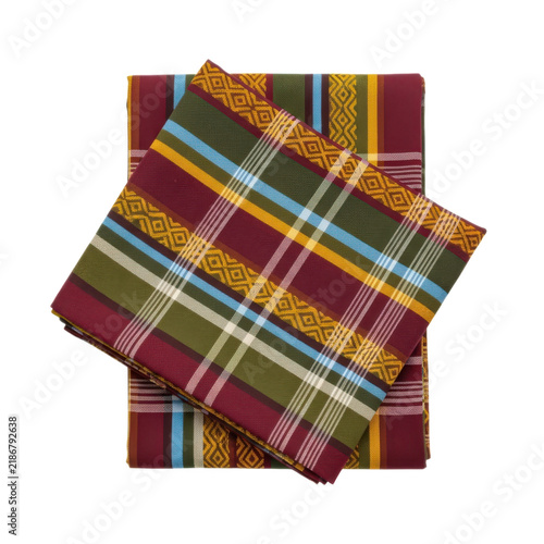 luxury ethnic textile fabric with vibrant plaid pattern featuring geometric diamond motifs in rich burgundy, olive green, yellow, and blue stripes folded on a white background