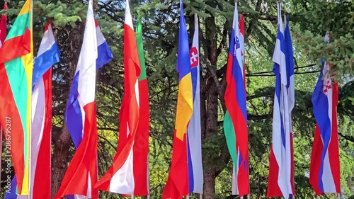 National flags on poles with trees on the background.