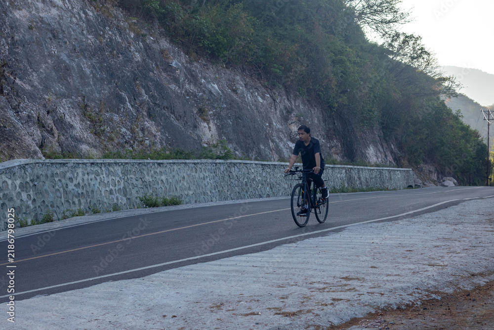 Fototapeta premium Cyclist Riding on a Mountain Road