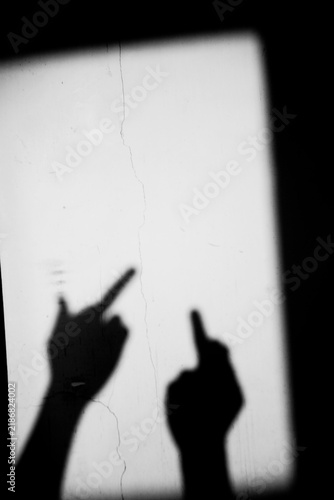 Foto Close up shadow of two hand showing middle finger gesture on the dirty wall