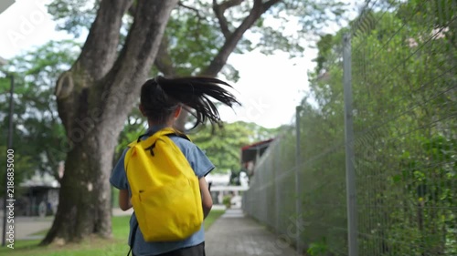 Asian girl with yellow backpack running to school