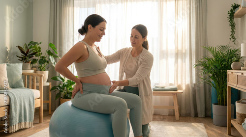 Pregnant woman sitting on stability ball with doula support during prenatal exercise, expressing calm focus in bright home interior