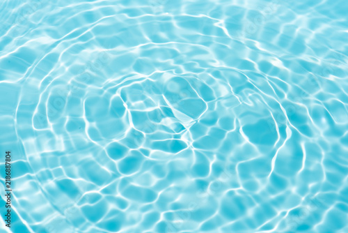 Bluewater waves on the surface ripples blurred. Defocus blurred transparent blue colored clear calm water surface texture with splash and bubbles. Water waves with shining pattern texture background.