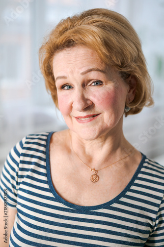 Картината върху платно Close up portrait of mature female in striped shirt tilting head and smiling warmly