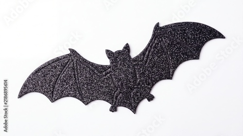 Silhouette of a bat with spread wings flying in night sky with stars and moon