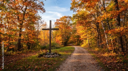 Wooden cross standing on a path in an autumn forest with vibrant foliage.