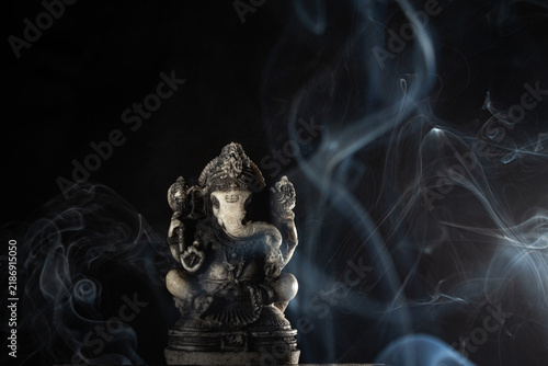 Ganesha statue with swirling incense smoke on a dark background for spiritual meditation