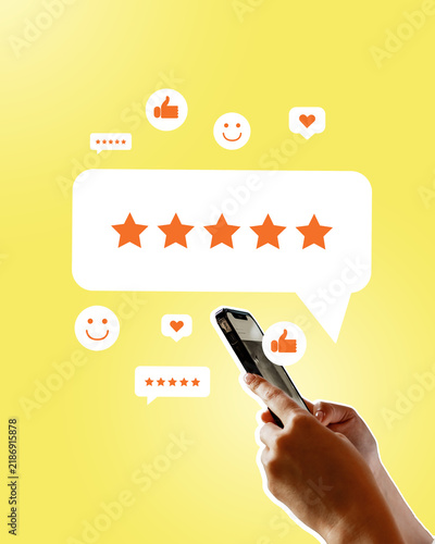 Person using smartphone to give five-star rating and feedback on a yellow background with review icons