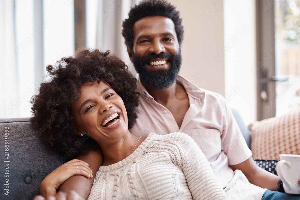 Obraz premium Relax, portrait and couple in home with coffee, connection and bonding together on weekend break. Chill, partner and African people with warm drink, happy moment and day off in romantic relationship.